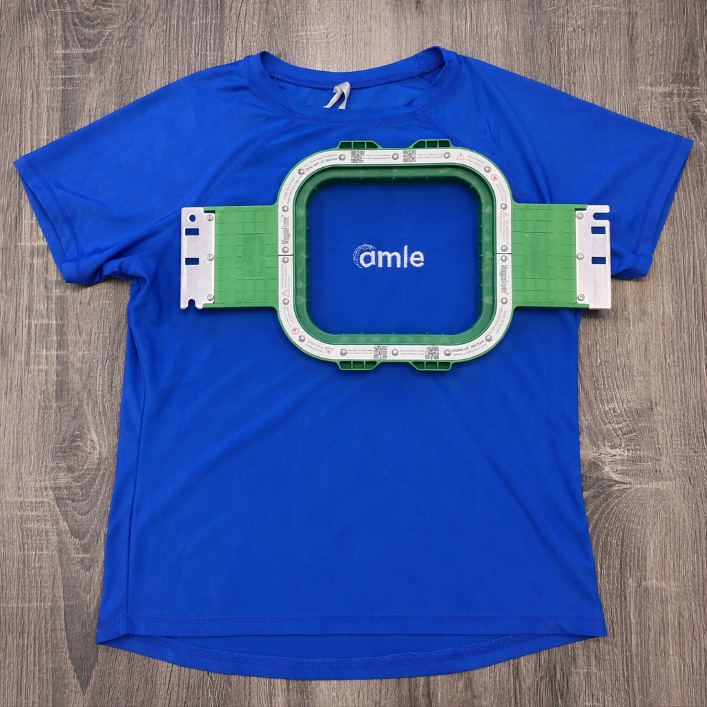 Blue t-shirt with a stadium graphic and 'amle' logo magnet hoop 5.1 in