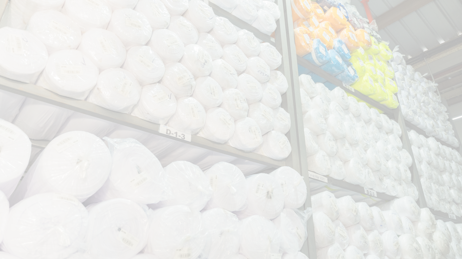 Close-up of white fabric rolls with colourful items partially visible