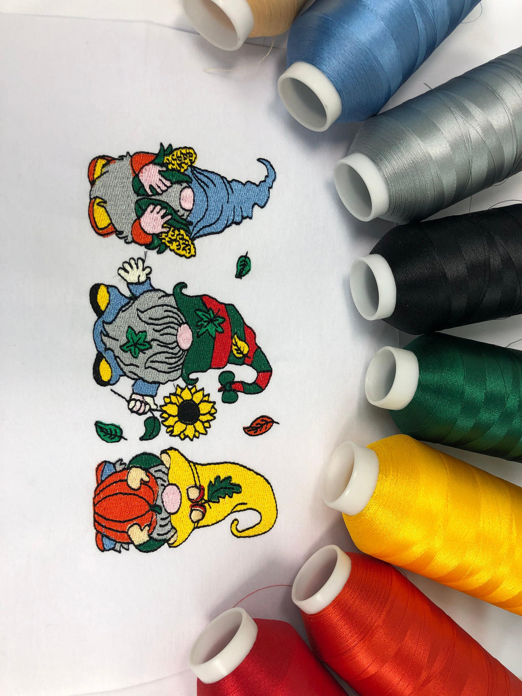 Embroidery floss spools with cartoon gnome designs on a white background