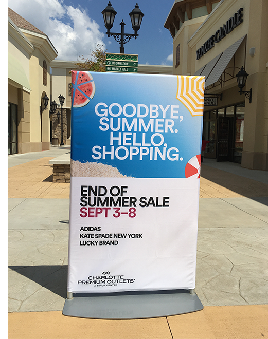 Use cases for sublimation fabric in marketing and advertising, showcasing and an end-of-summer sale sign at Charlotte Premium Outlets, with the store exterior in the background.